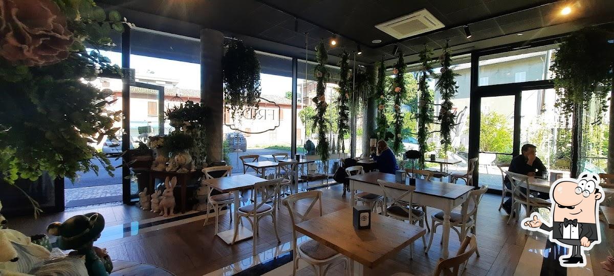 Sala interna Frida con sedie bianche e felci sospese, vista sulla piazza
